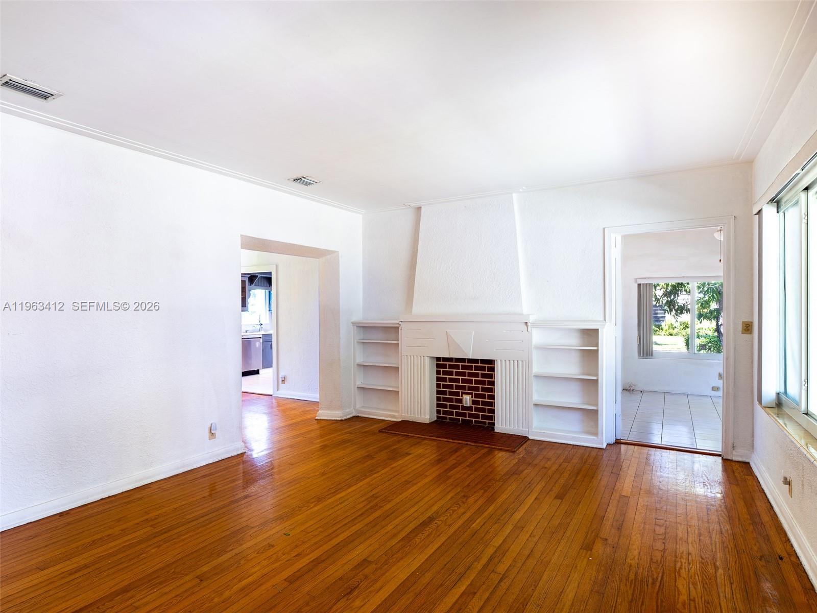 630 Southwest 25th Road Miami, FL 33129 - Photo 6 of 35 a view of empty room with wooden floor and fireplace