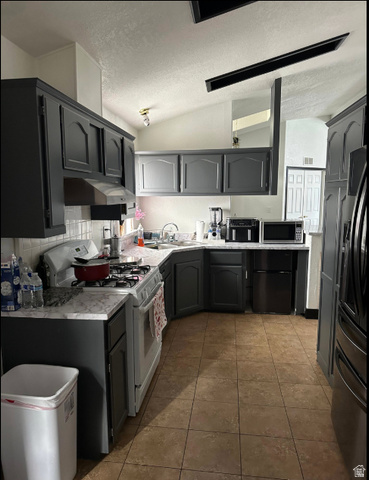 265 Mindella Way Layton, UT 84041 - Photo 11 of 32 Kitchen featuring dark gray cabinetry, light-toned countertops, a white gas range, and warm-toned tile flooring