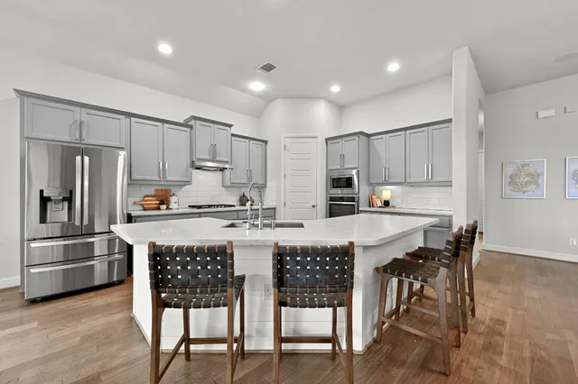 a kitchen with kitchen island granite countertop a table chairs stainless steel appliances and cabinets