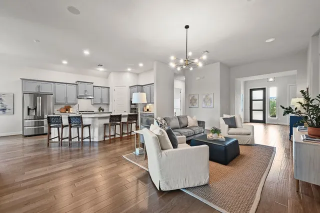a living room with furniture kitchen view and a chandelier