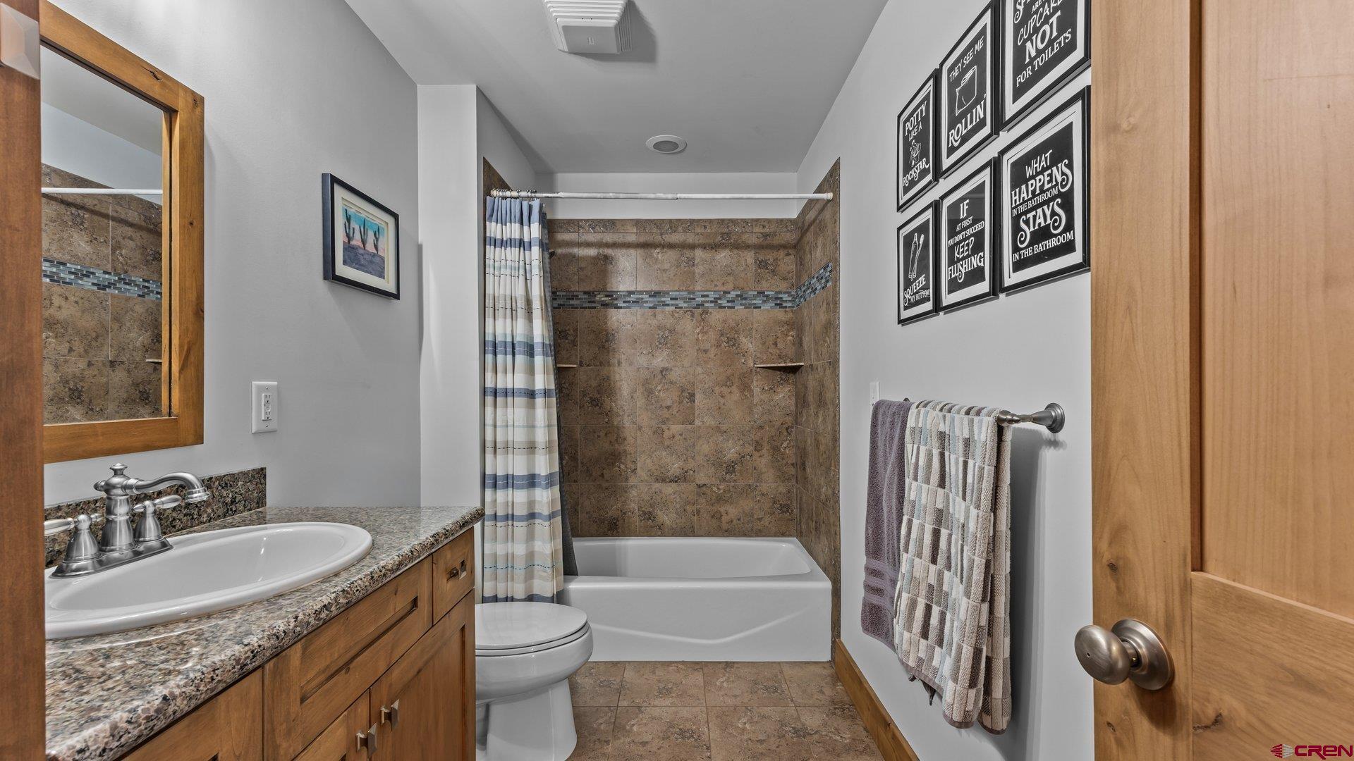 2601 South 21 1/2 Road Glade Park, CO 81523 - Photo 39 of 45 a bathroom with a granite countertop sink a toilet a mirror a bathtub and shower