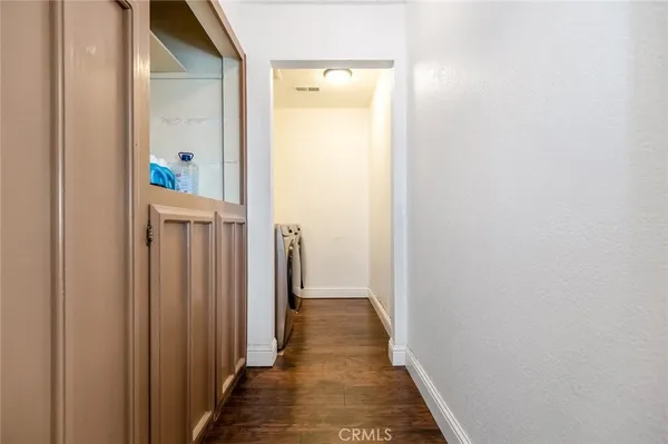 a view of a hallway with wooden floor and a bathroom
