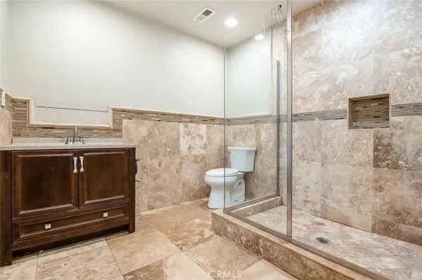 a bathroom with a granite countertop sink a toilet and a shower