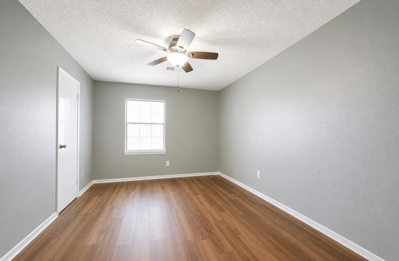 3728 Autumn Lane Baytown, TX 77521 - Photo 13 of 16 This room features a clean, modern design with light gray walls and warm wood flooring. A ceiling fan provides comfort, and a single window allows natural light to fill the space. Perfect for a cozy bedroom or office.