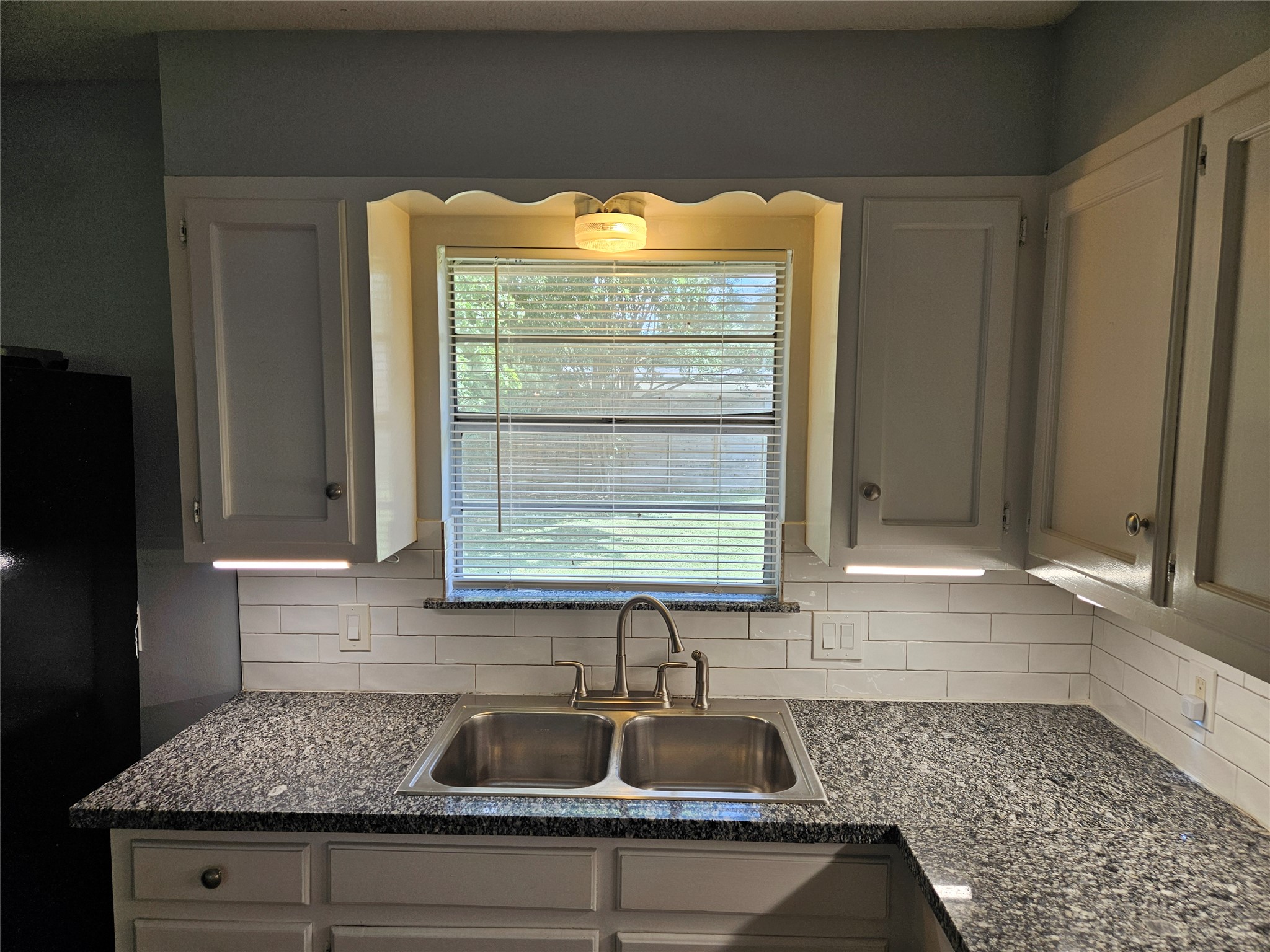 806 Ranch Road, Unit A Georgetown, TX 78628 - Photo 9 of 24 A well-equipped kitchen features a dual basin sink set against granite countertops and white subway tile.