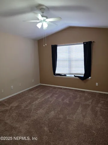 a view of a room that has a window and a ceiling fan