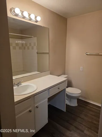 a bathroom with a granite countertop sink toilet and a mirror