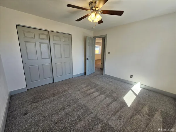 a view of an empty room and chandelier fan