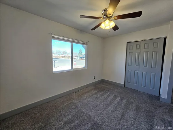 a view of an empty room with window and chandelier fan