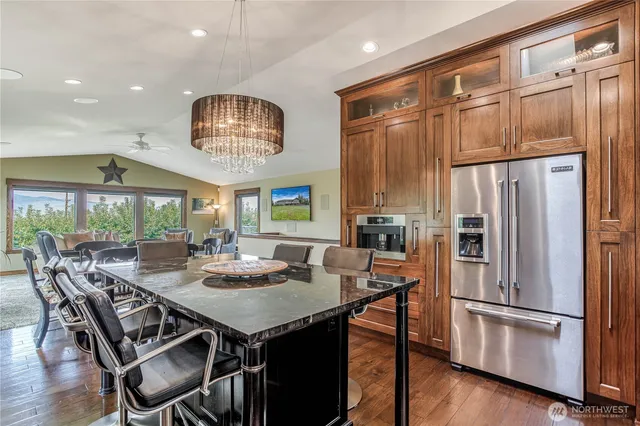 a kitchen with stainless steel appliances granite countertop a stove refrigerator a dining table and chairs with wooden floor