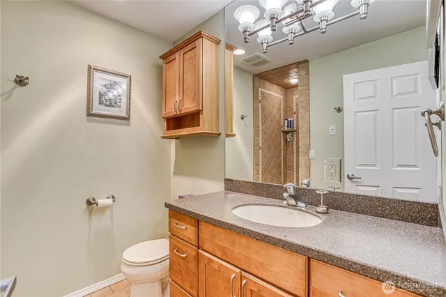 a bathroom with a granite countertop sink a toilet and a mirror