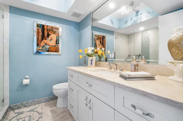 a bathroom with a granite countertop sink mirror vanity and toilet