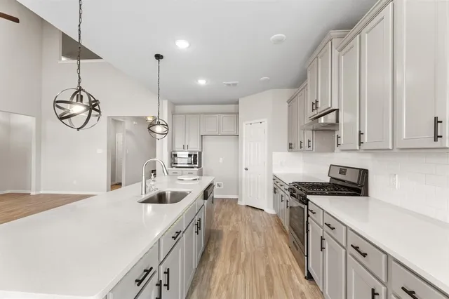 a kitchen with stainless steel appliances a sink stove and cabinets