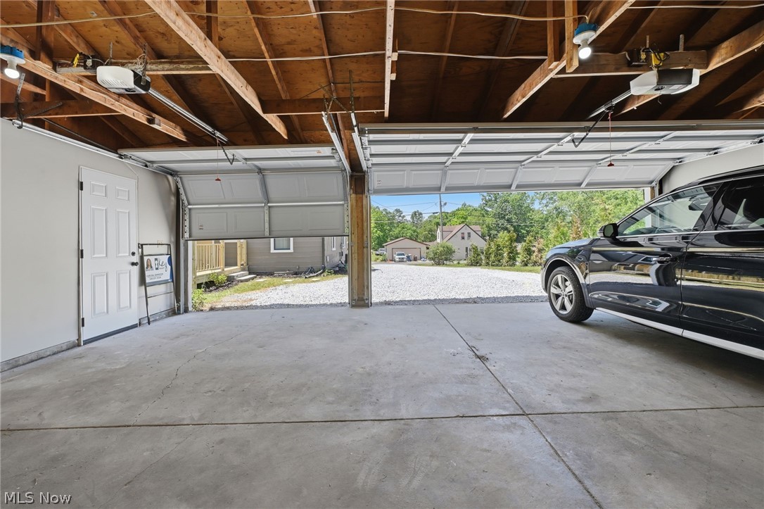 951 Bey Road Akron, OH 44312 - Photo 29 of 34 Three-car garage featuring concrete flooring, exposed wood beam ceiling, automatic garage door opener and a side access door