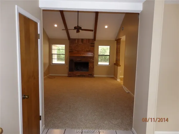 a view of an empty room with a fireplace and a window