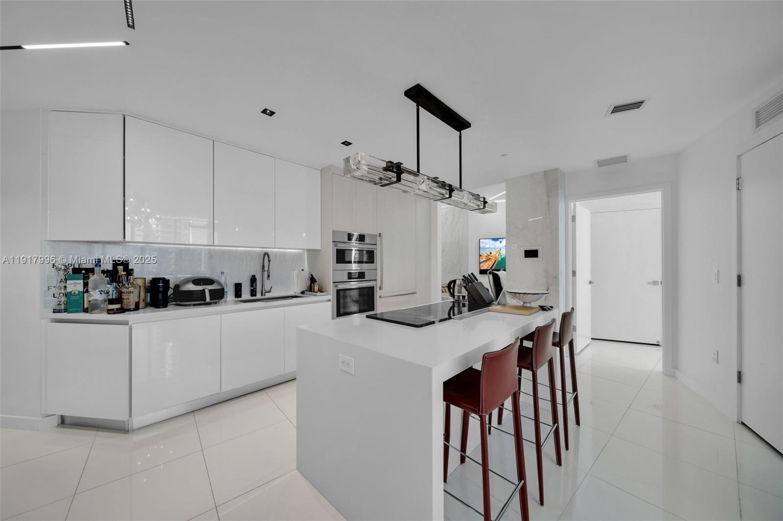 851 Northeast 1st Avenue, Unit 2203 Miami, FL 33132 - Photo 40 of 53 a kitchen with stainless steel appliances kitchen island a table chairs in it and white cabinets