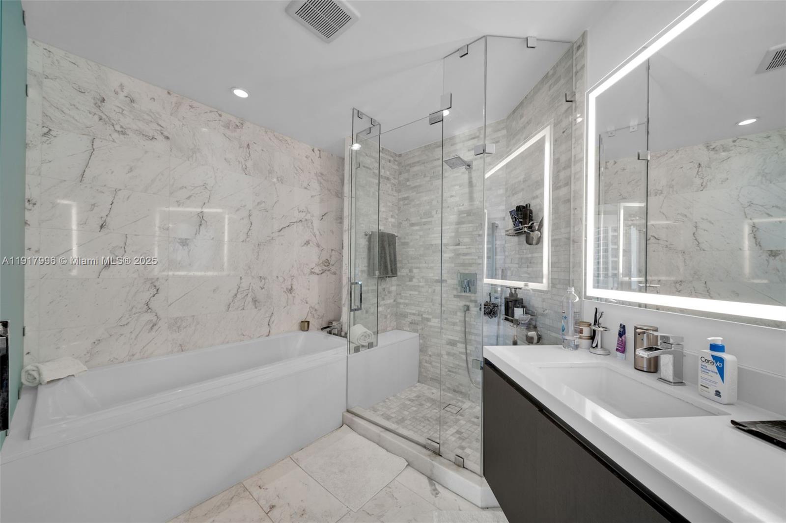 851 Northeast 1st Avenue, Unit 2203 Miami, FL 33132 - Photo 45 of 53 a bathroom with a granite countertop sink a mirror a bathtub and shower