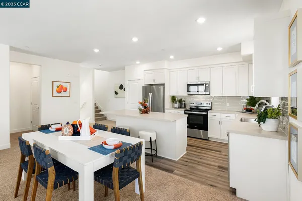 a kitchen with a table chairs a sink dishwasher a stove a microwave oven a dining table and chairs