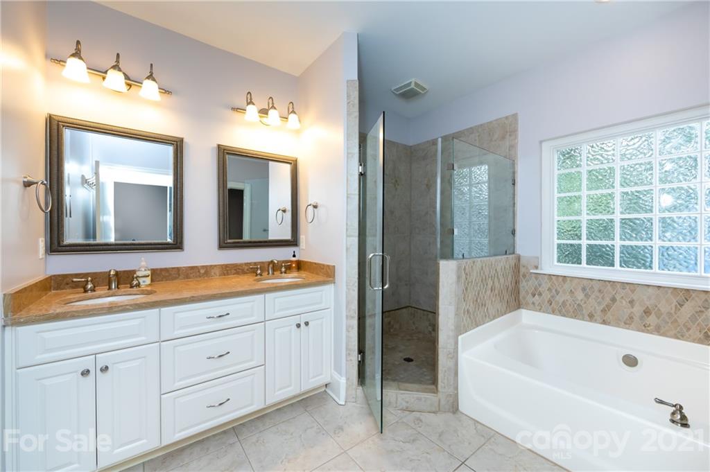 817 Millbrook Road Charlotte, NC 28211 - Photo 15 of 26 a bathroom with a tub a double vanity sink and a large mirror