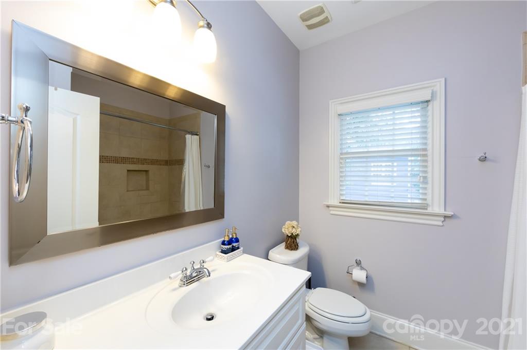 817 Millbrook Road Charlotte, NC 28211 - Photo 18 of 26 a bathroom with a toilet a sink a mirror and a window