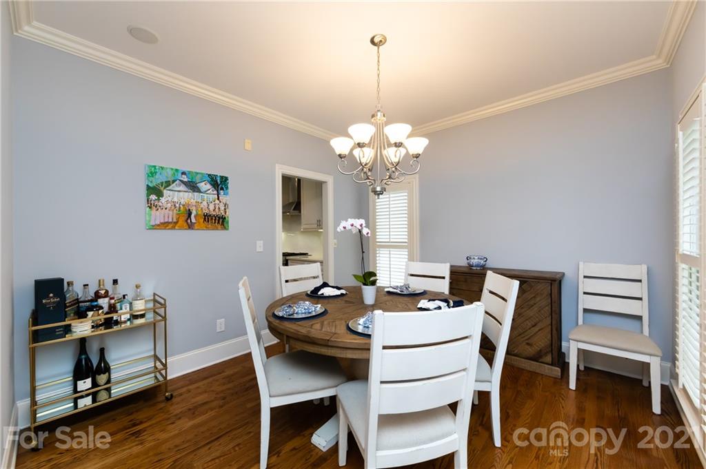 817 Millbrook Road Charlotte, NC 28211 - Photo 4 of 26 a dining room with wooden floor a chandelier a wooden table and chairs