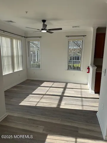 a view of an empty room with a window and wooden floor