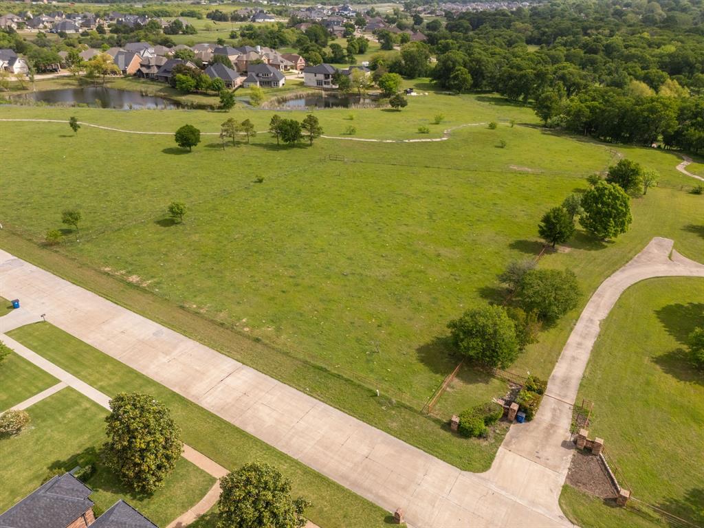 Tbd Sleepy Hollow Road Ennis, TX 75119 - Photo 3 of 11 Expansive green property with a paved road, mature trees, and a distant view of residential properties and a body of water