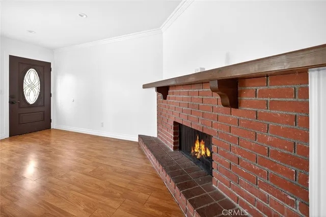 a view of an empty room with wooden floor and a fireplace