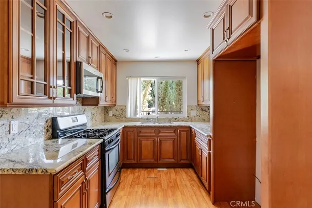 a kitchen with stainless steel appliances granite countertop a stove a sink and a microwave