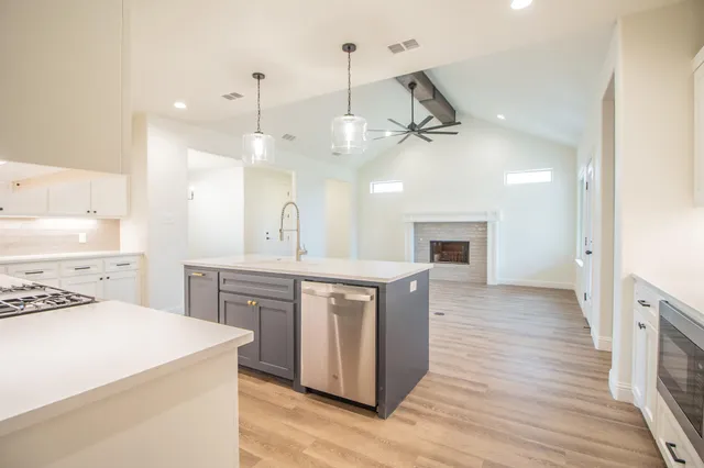 a large kitchen with cabinets a sink and stainless steel appliances