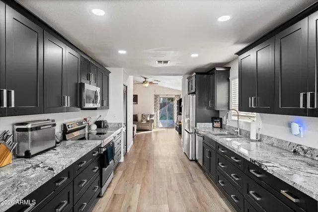 a large kitchen with stainless steel appliances granite countertop plenty wooden cabinets counter space a sink and wooden floor