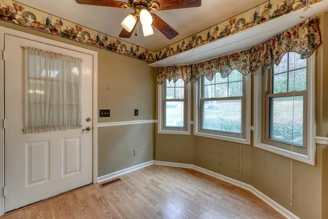 an empty room with wooden floor fan and windows