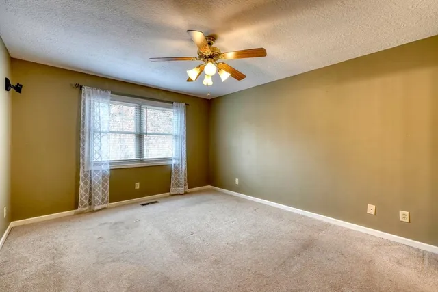 an empty room with windows and chandelier fan