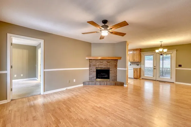 a view of a livingroom with a fireplace a ceiling fan and wooden floor