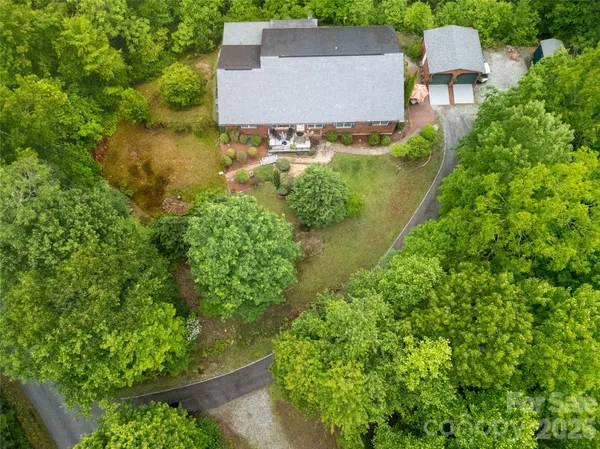 an aerial view of residential house with outdoor space and trees all around