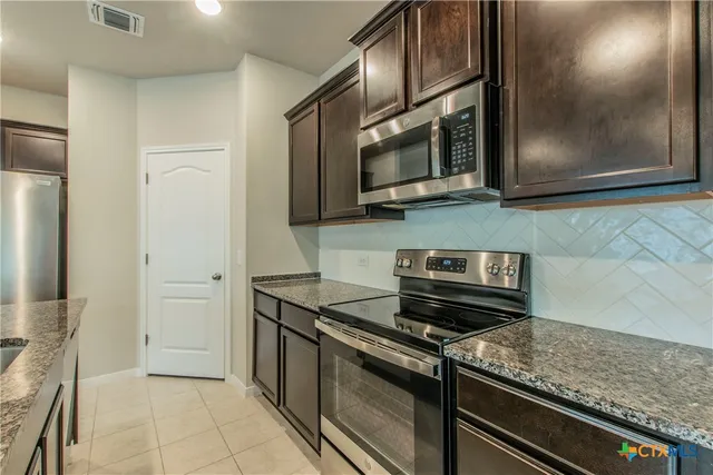 a kitchen with stainless steel appliances granite countertop a stove and a microwave
