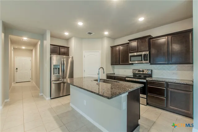 a kitchen with stainless steel appliances granite countertop a sink stove and refrigerator