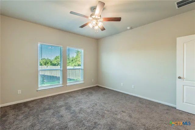 an empty room with windows and fan