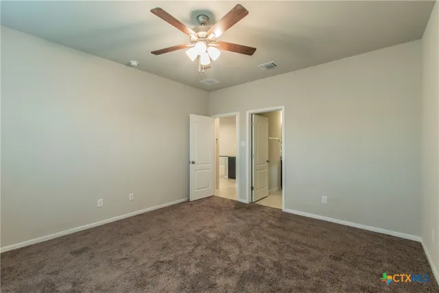 an empty room with a chandelier fan and windows