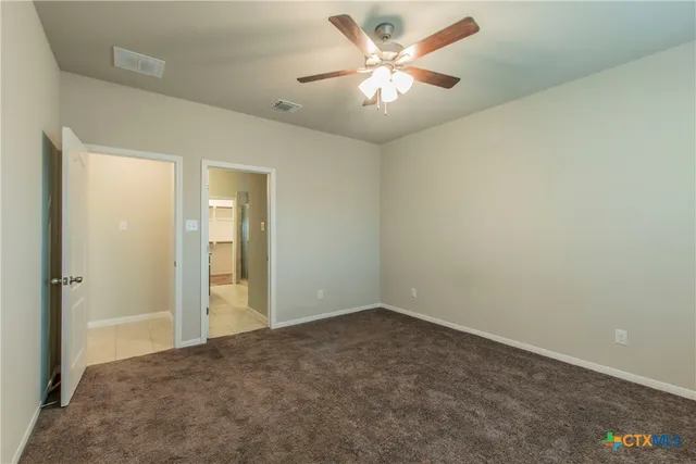 an empty room with a chandelier fan and windows