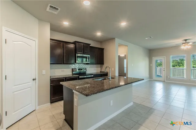 a kitchen with stainless steel appliances granite countertop a stove a sink and a refrigerator