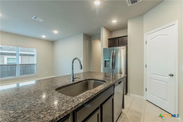 a kitchen with stainless steel appliances granite countertop a sink a stove and a refrigerator