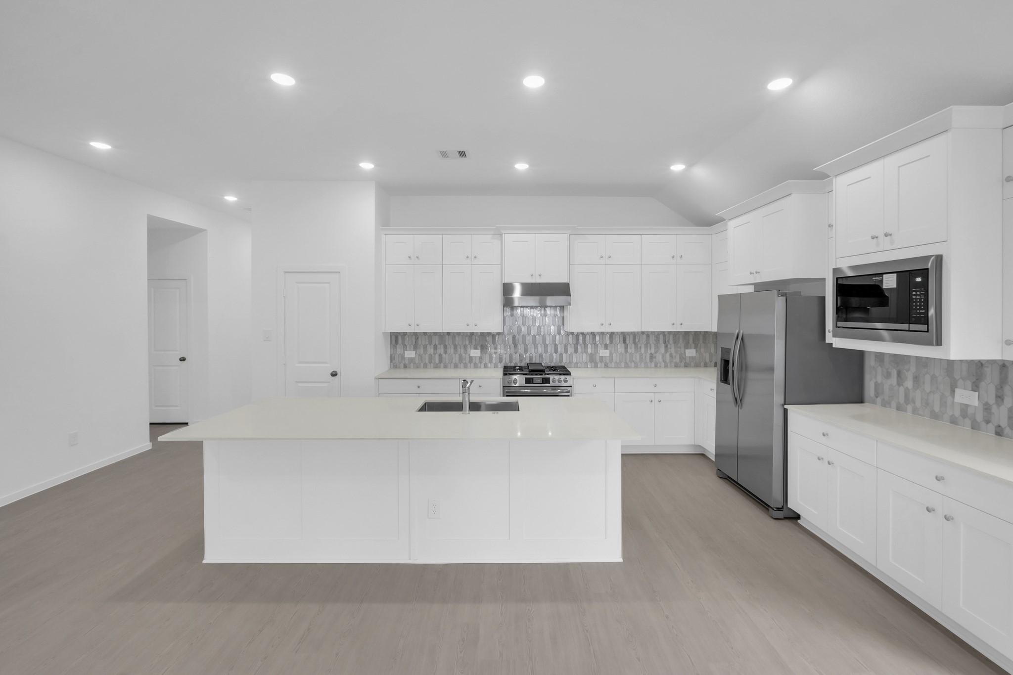 2135 Mosaic Vly Court Angleton, TX 77515 - Photo 4 of 15 a large kitchen with kitchen island a sink a stove a refrigerator and white cabinets