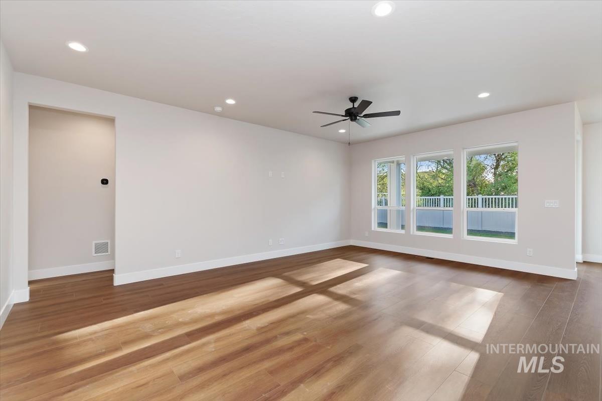 Spacious room featuring wood-finish flooring, recessed lighting, and a contemporary ceiling fan