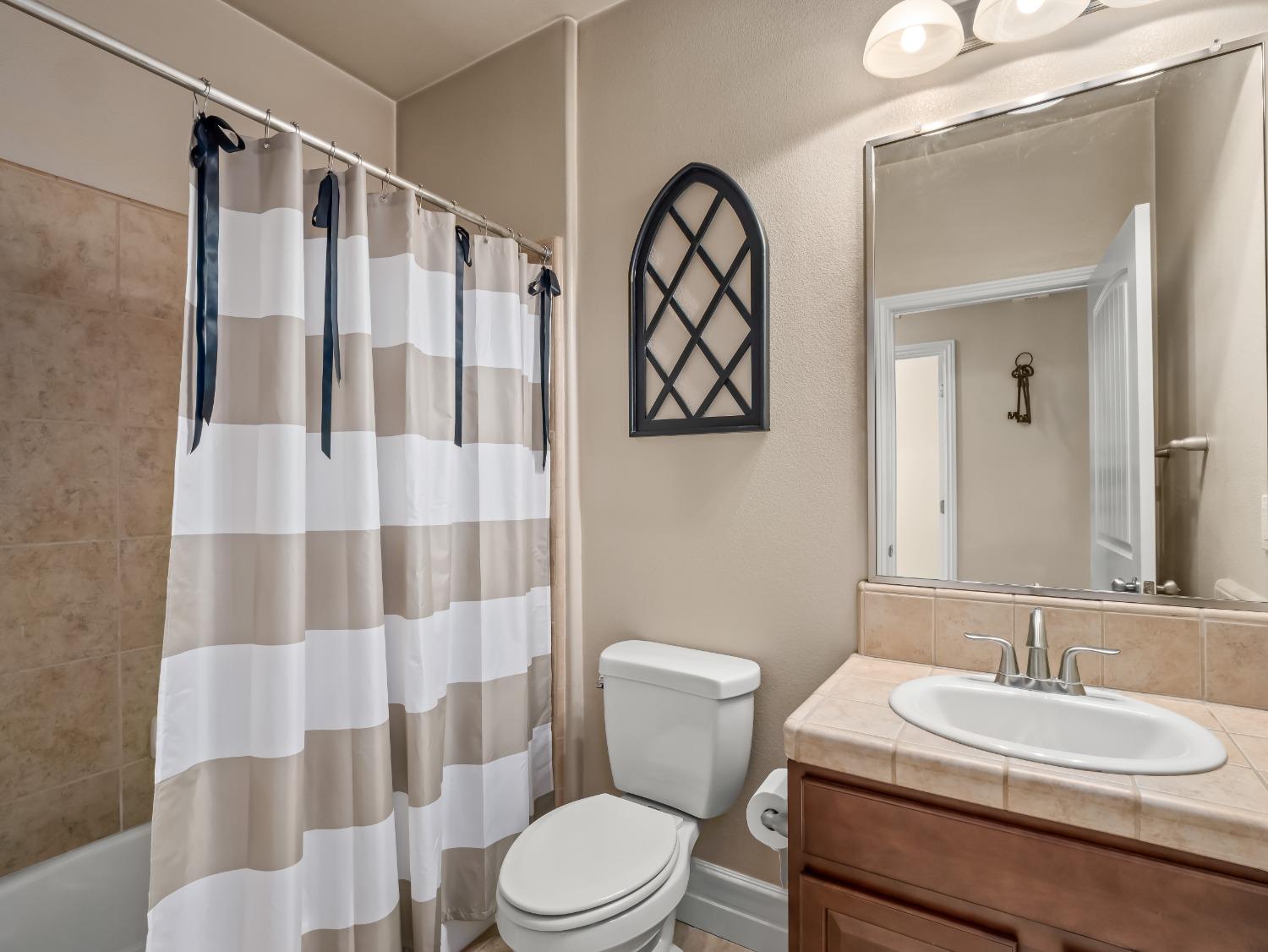 948 Whitmore Avenue Clovis, CA 93619 - Photo 15 of 38 a bathroom with a sink a toilet a shower curtain and a mirror