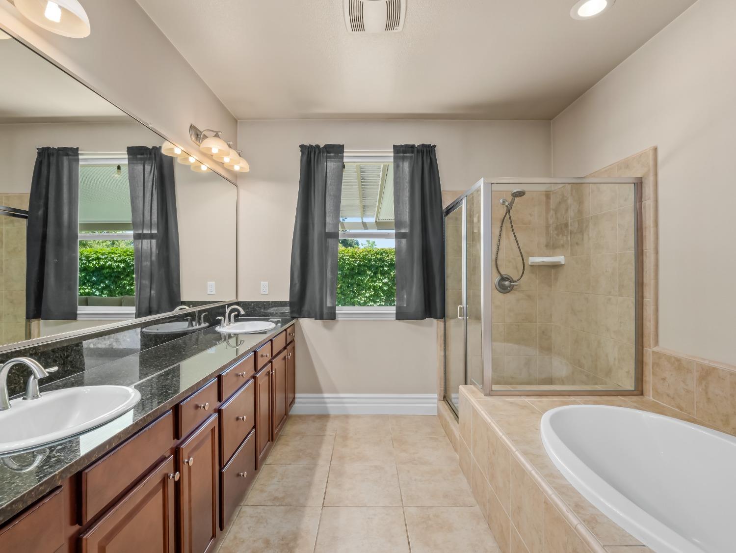 948 Whitmore Avenue Clovis, CA 93619 - Photo 22 of 38 a spacious bathroom with a granite countertop tub sink a mirror a shower and vanity