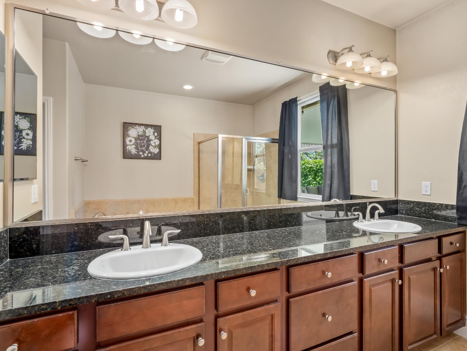 948 Whitmore Avenue Clovis, CA 93619 - Photo 23 of 38 a bathroom with a granite countertop sink a large mirror and a window