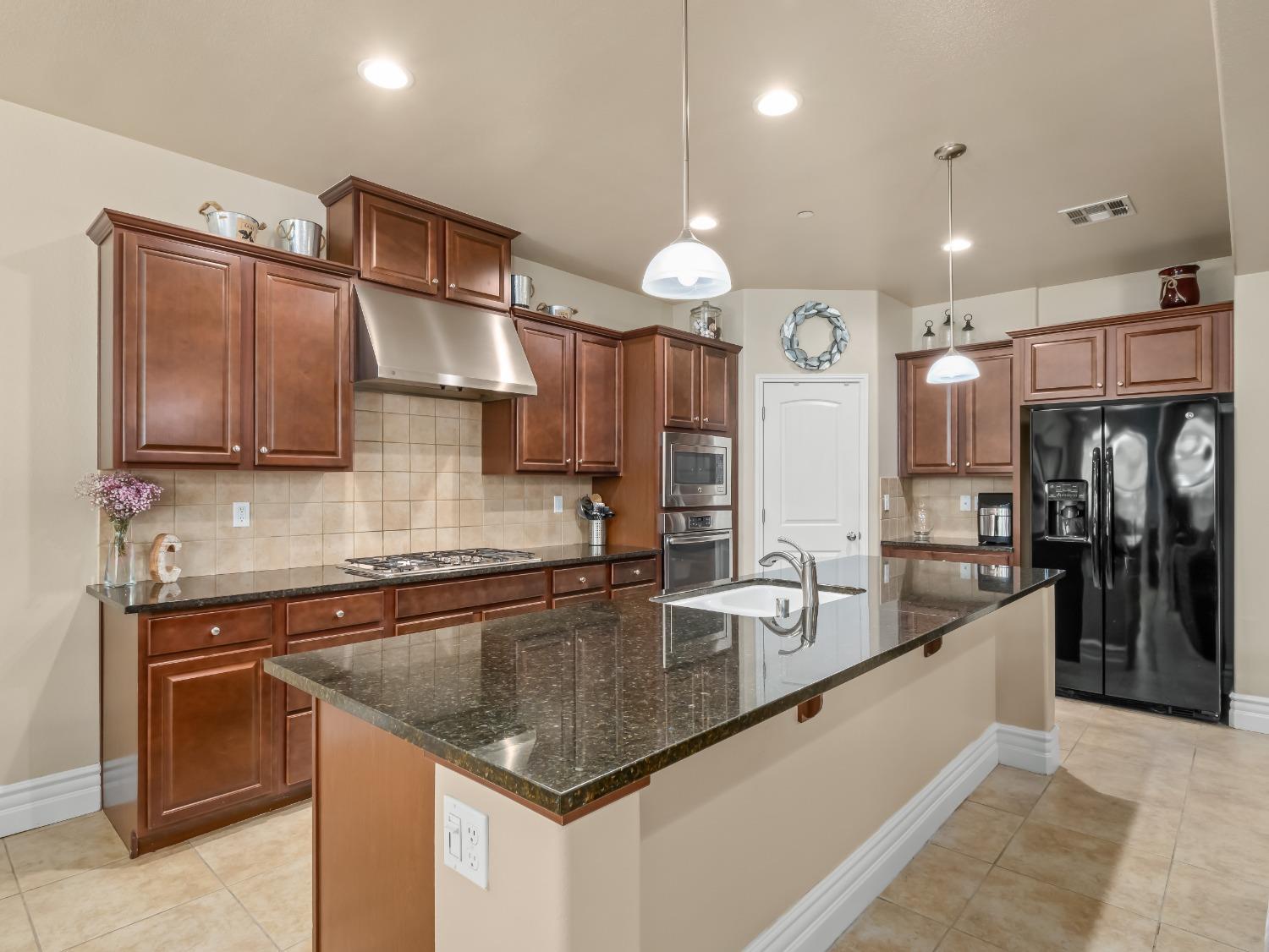 948 Whitmore Avenue Clovis, CA 93619 - Photo 6 of 38 a kitchen with stainless steel appliances granite countertop a sink a stove and a refrigerator