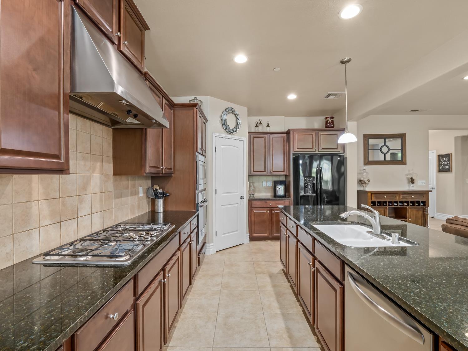 948 Whitmore Avenue Clovis, CA 93619 - Photo 8 of 38 a kitchen with stainless steel appliances granite countertop a sink stove and refrigerator