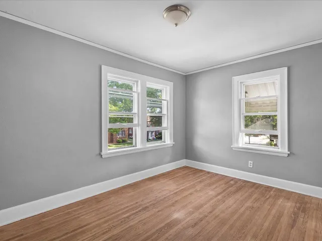 a view of an empty room with wooden floor and closet